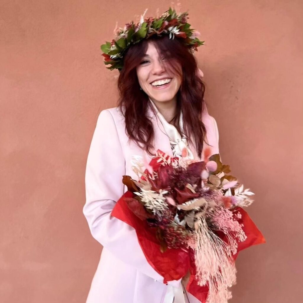Alessia Rodighiero con corona d'alloro in testa tiene in mano un bouquet di fiori per festeggiare il conseguimento della laurea.