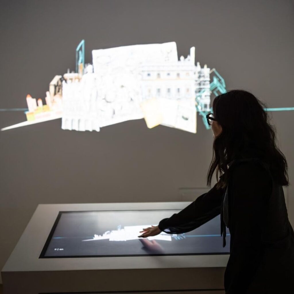 Alessia Rodighiero tocca un display per "interagire" con un'opera proiettata sul muro.