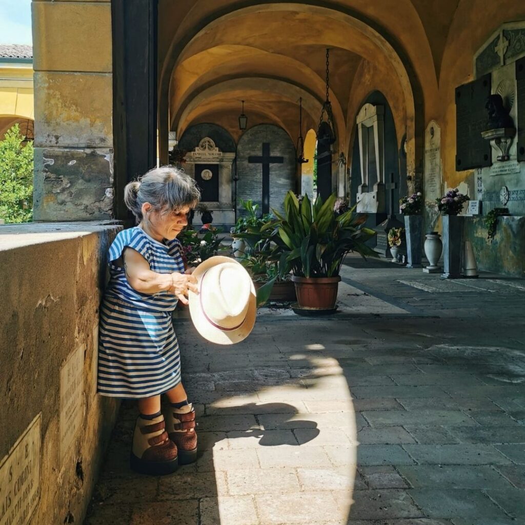 Francesca Moscardo appoggiata a una parete tiene in mano un cappello di paglia.