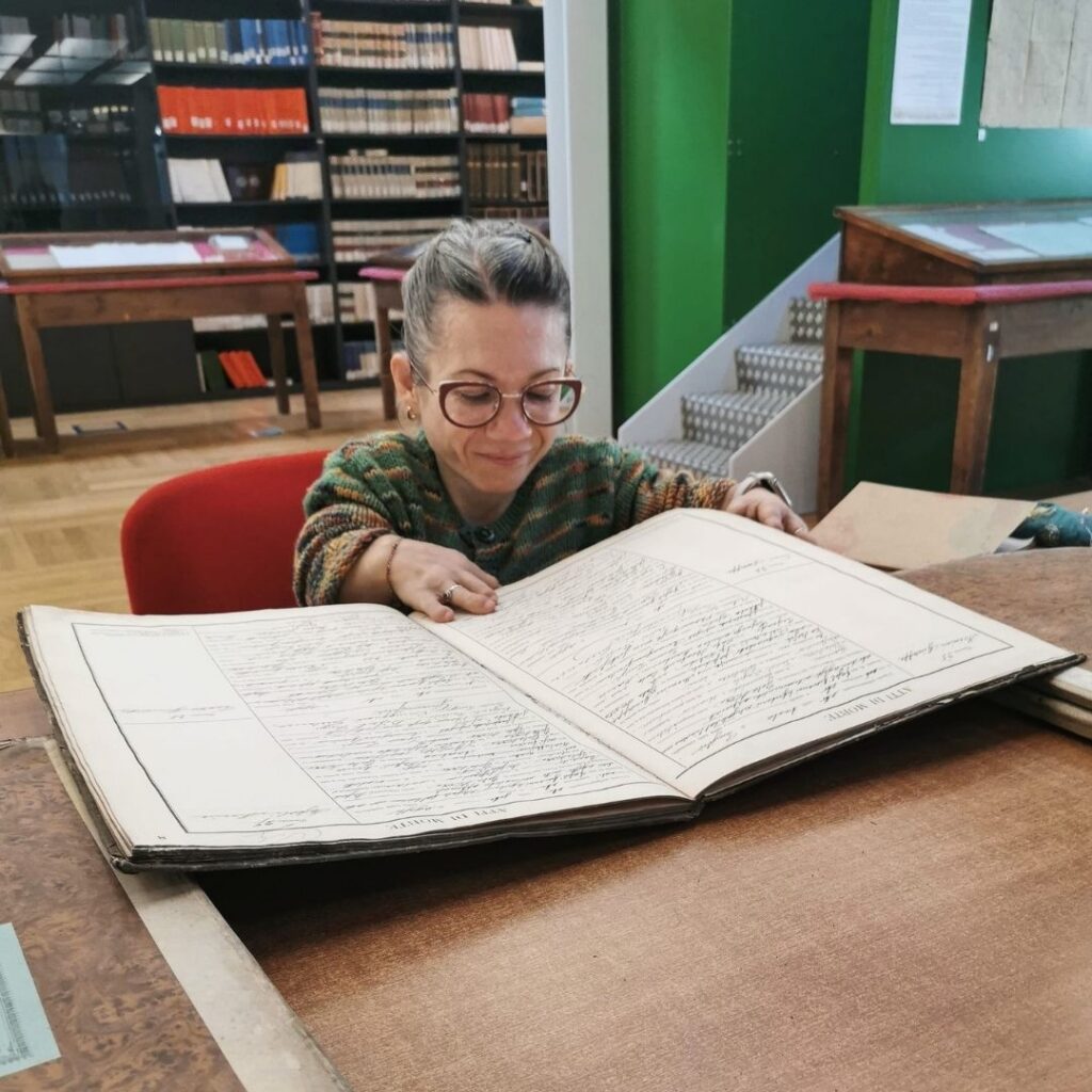 Francesca Moscardo intenta a sfogliare un registro all'interno di un archivio.