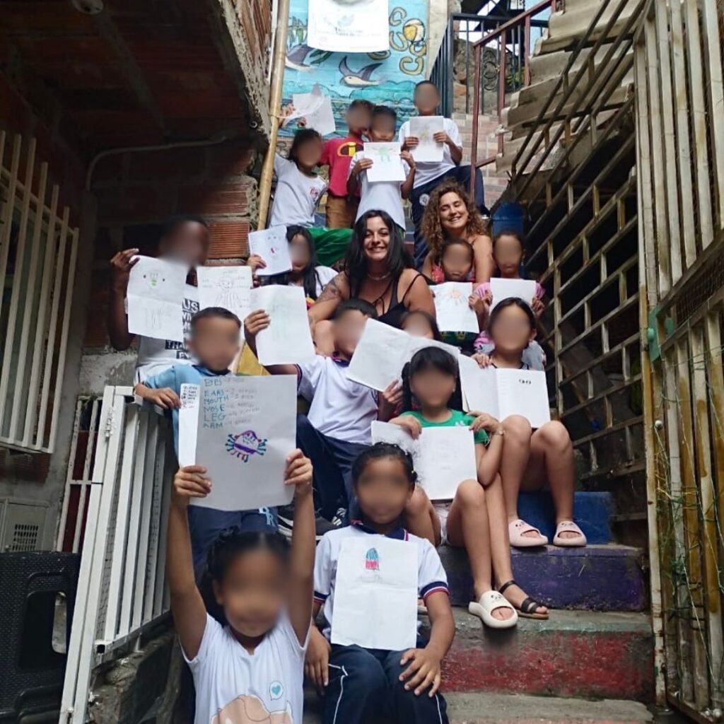Irene De Pascalis posa seduta su una scalinata insieme a un'altra ragazza e alcuni bambini