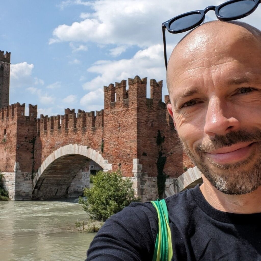 Primo piano di Alessandro Fin. Sullo sfondo Castelvecchio e il fiume Adige