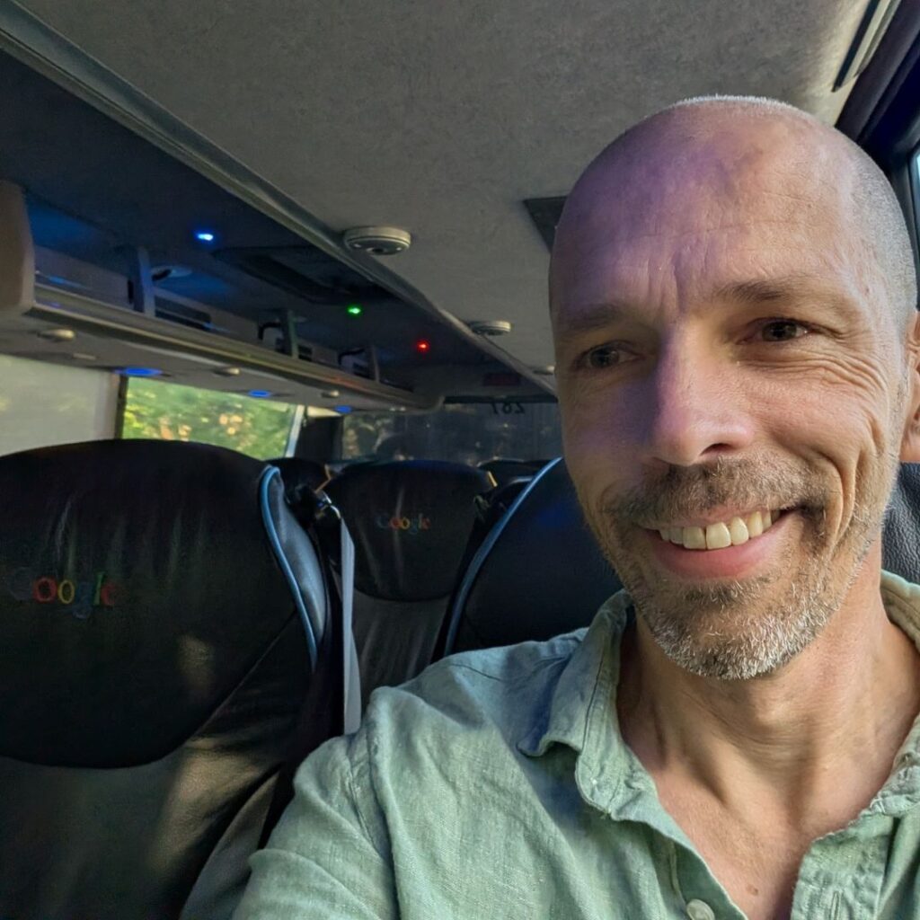 Alessandro Fin in primo piano seduto all' interno di un autobus di Google