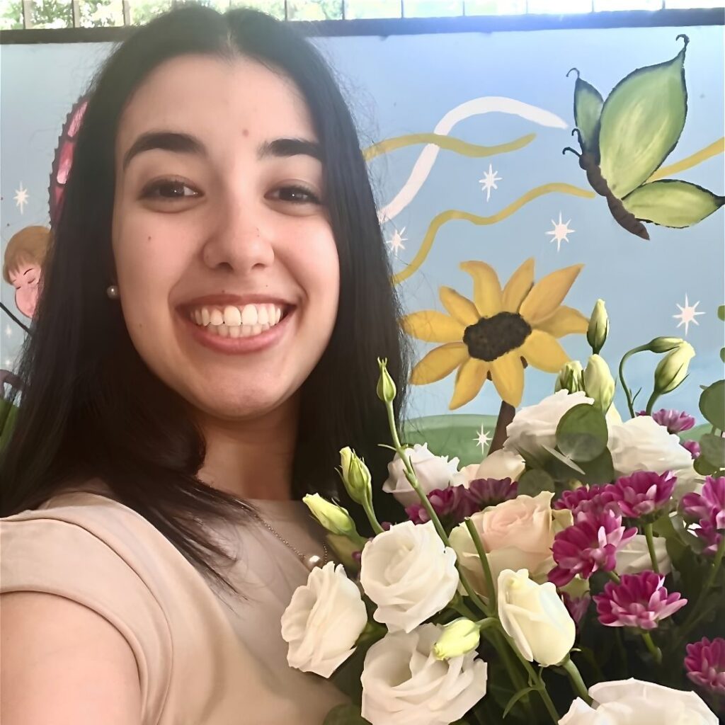 Camilla Pirrello posa sorridente con un mazzo di fiori in mano
